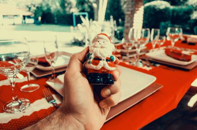 Main tenant une figurine de Père Noël sur une table festive en plein air, idéale pour les célébrations de Noël