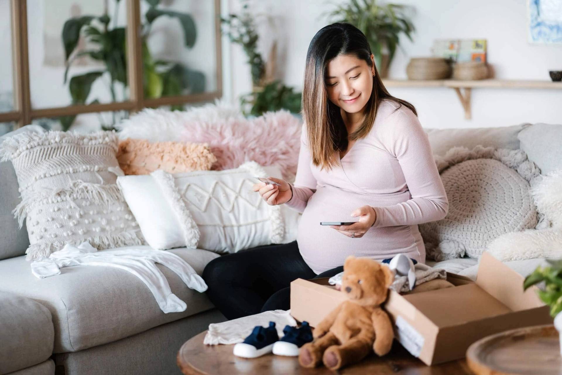 Femme au ventre arrondi découvrant des accessoires pour bébé.