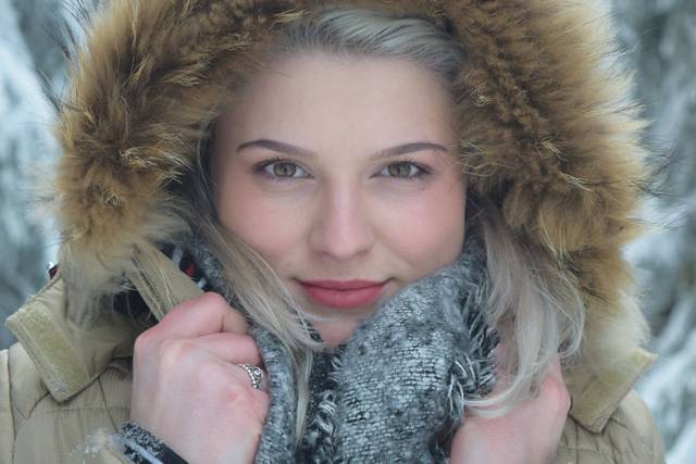 Portrait d'hiver en gros plan d'une femme dans une veste à capuche en fourrure avec une écharpe