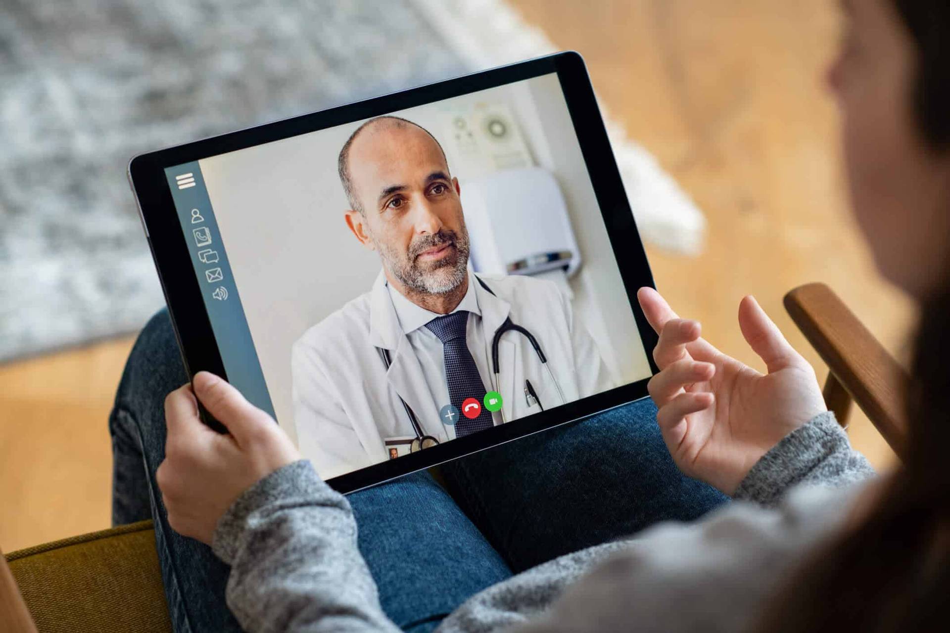 Consultation vidéo avec un homme en blouse sur une tablette.