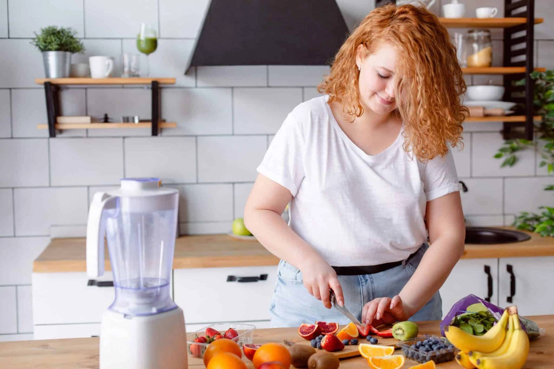 Femme préparant des fruits et légumes dans une cuisine.