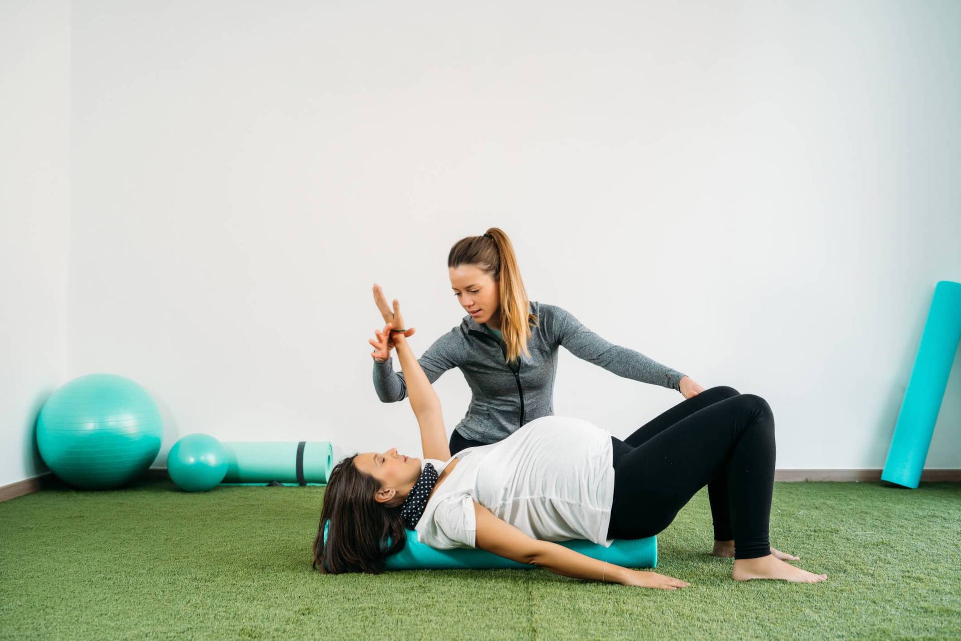 Professionnelle accompagnant une femme dans un exercice au sol.