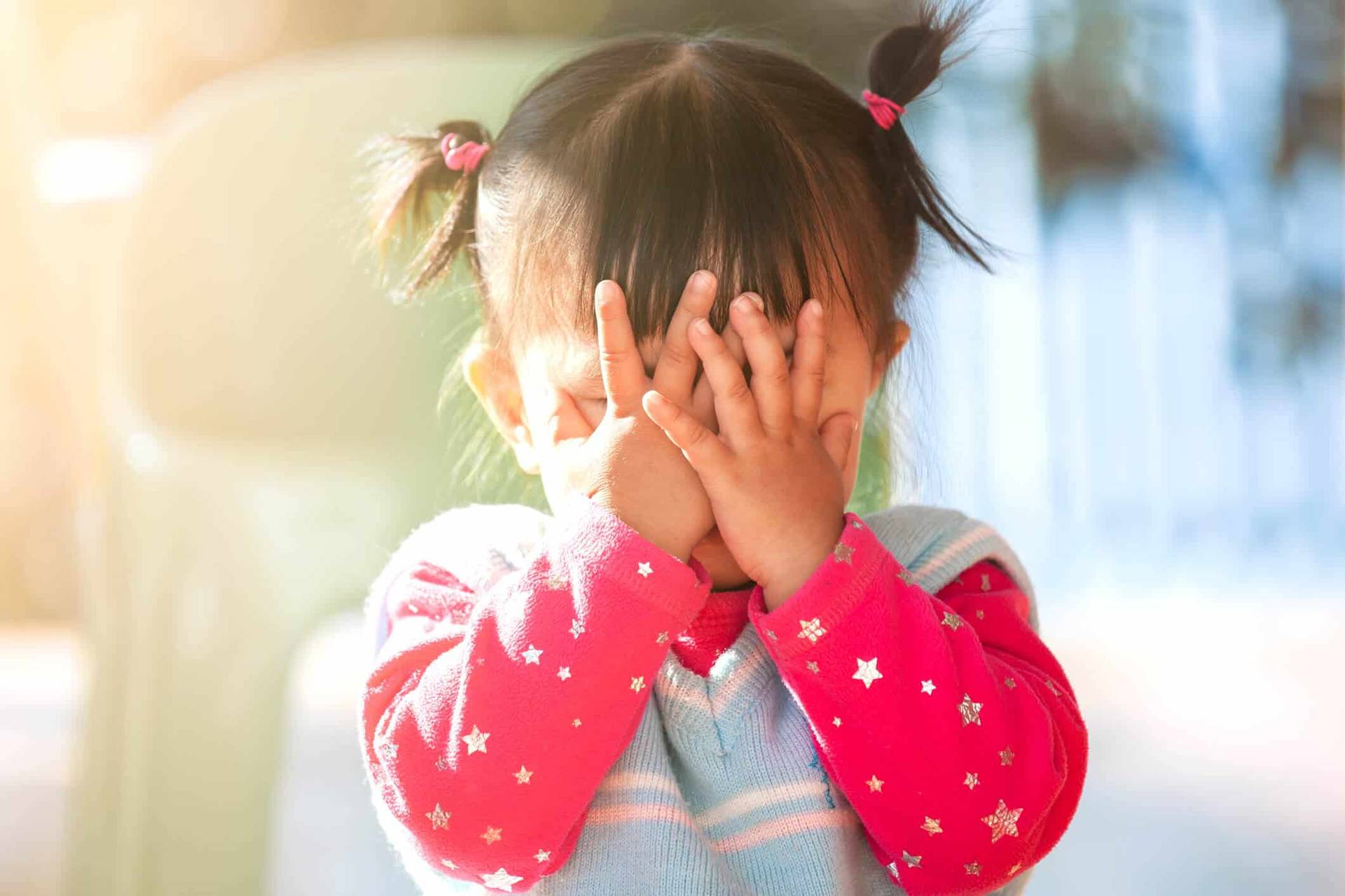Enfant se frottant les yeux avec les mains.