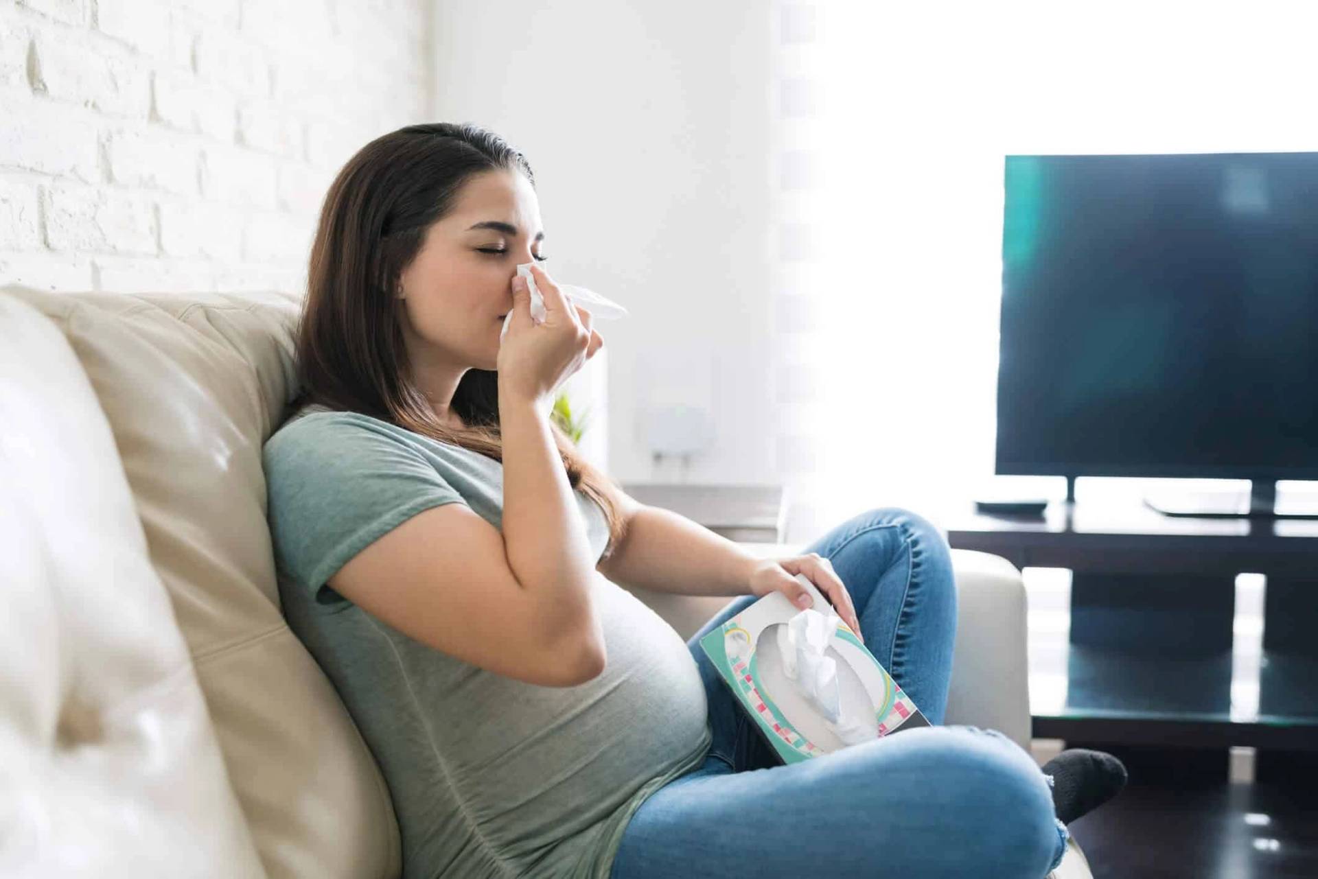 Femme enceinte assise, tenant un mouchoir devant le nez.