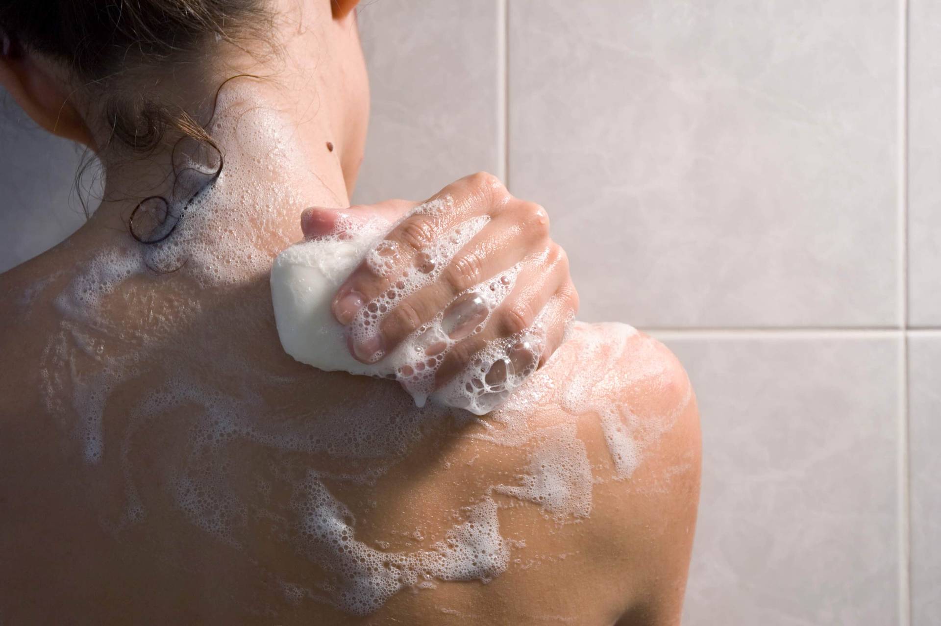 Personne se savonnant l’épaule sous la douche.