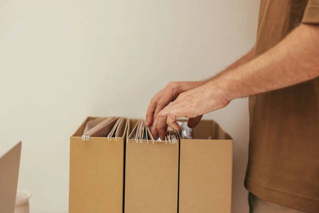 Gros plan d'une personne organisant des fichiers dans des boîtes en carton, idéal pour des thèmes professionnels