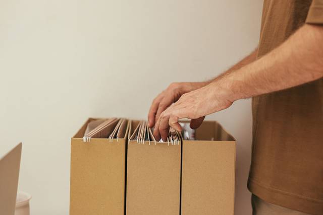 Gros plan d'une personne organisant des fichiers dans des boîtes en carton, idéal pour des thèmes professionnels