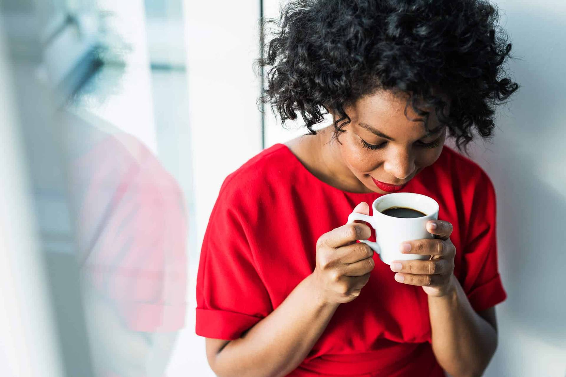 Femme approchant une tasse de son nez.