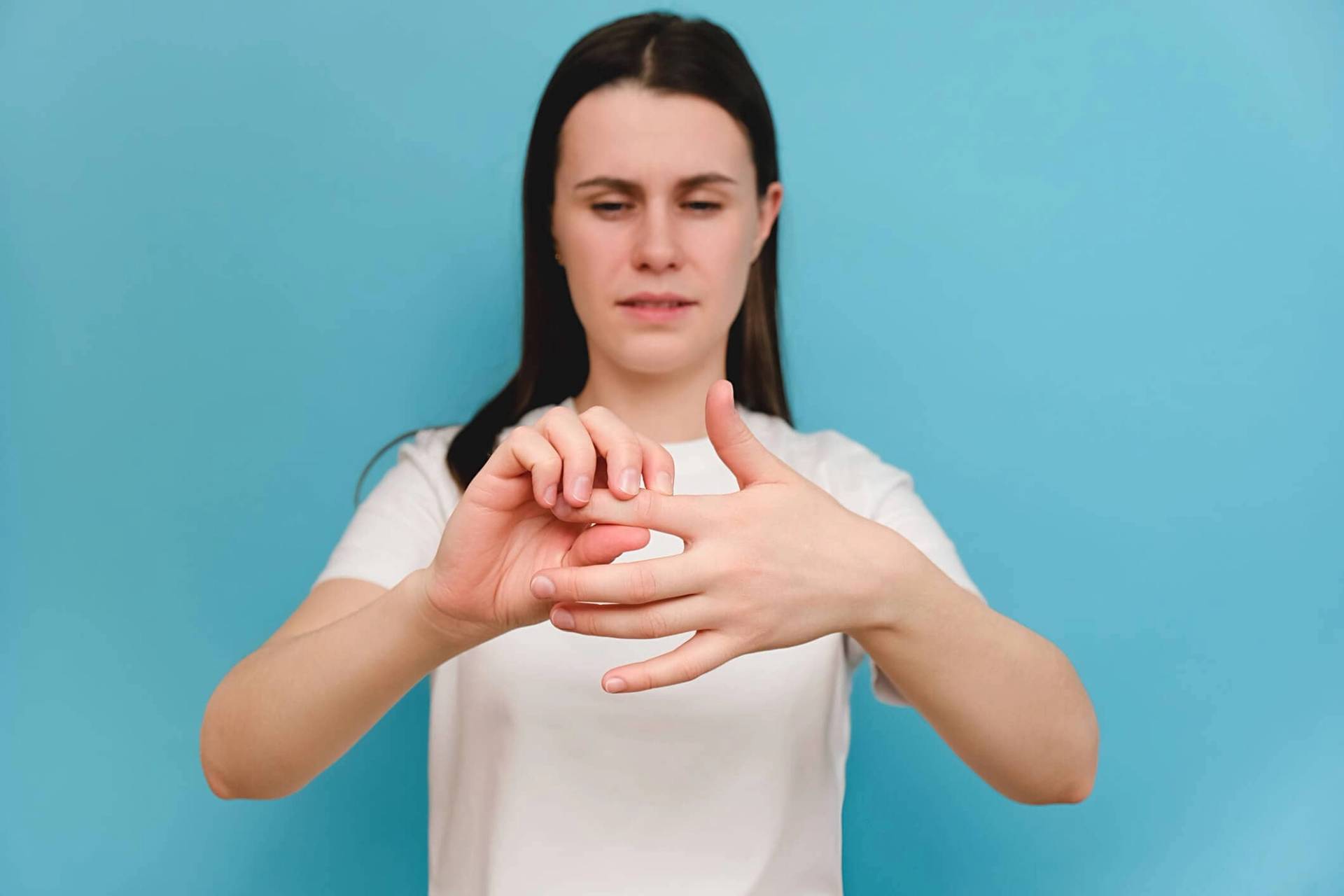 Femme massant un doigt avec l’autre main.