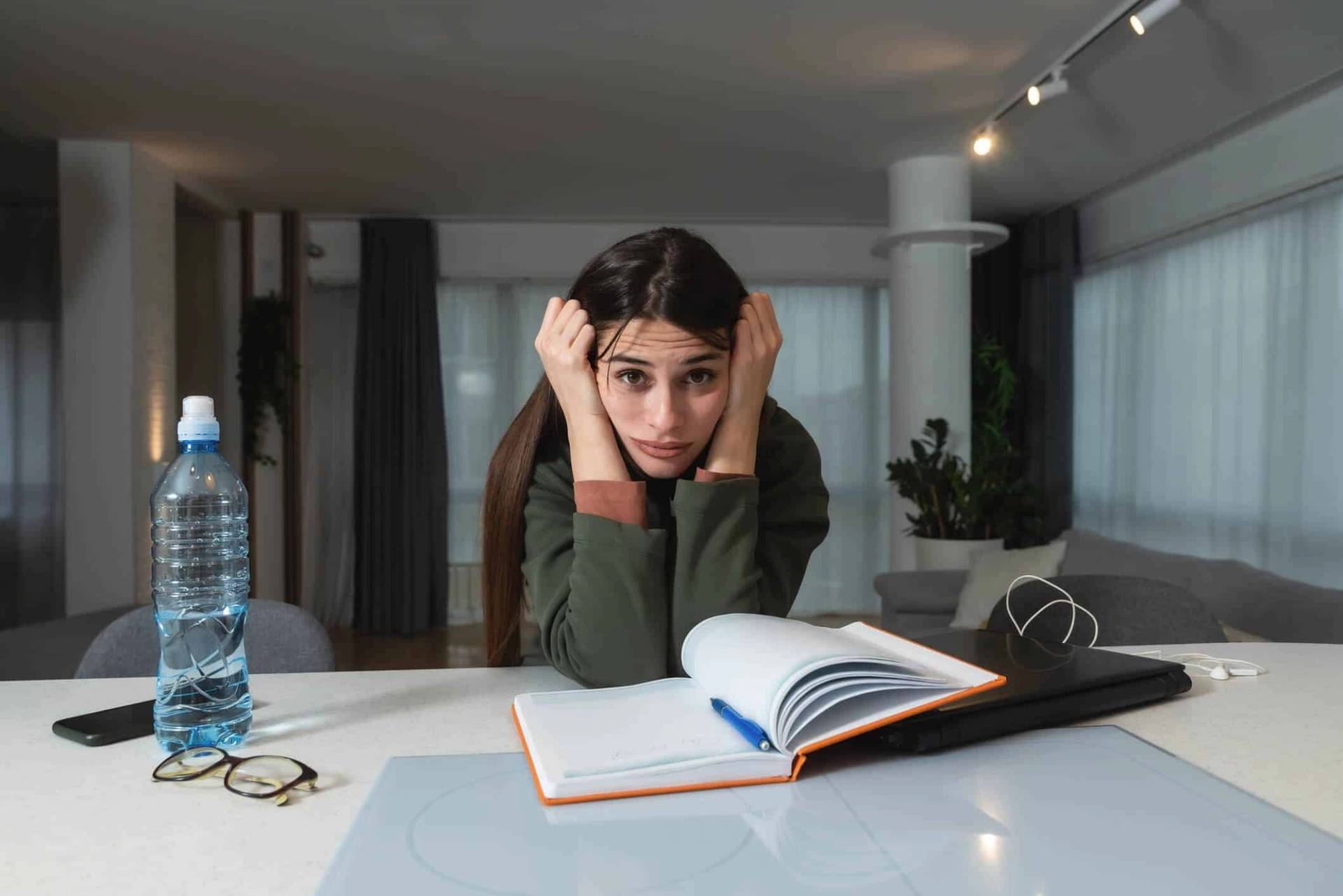Jeune femme devant un livre ouvert, la tête dans les mains.