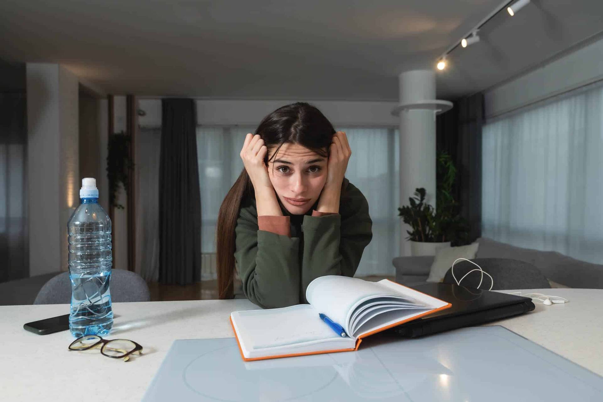 Jeune femme devant un livre ouvert, la tête dans les mains.