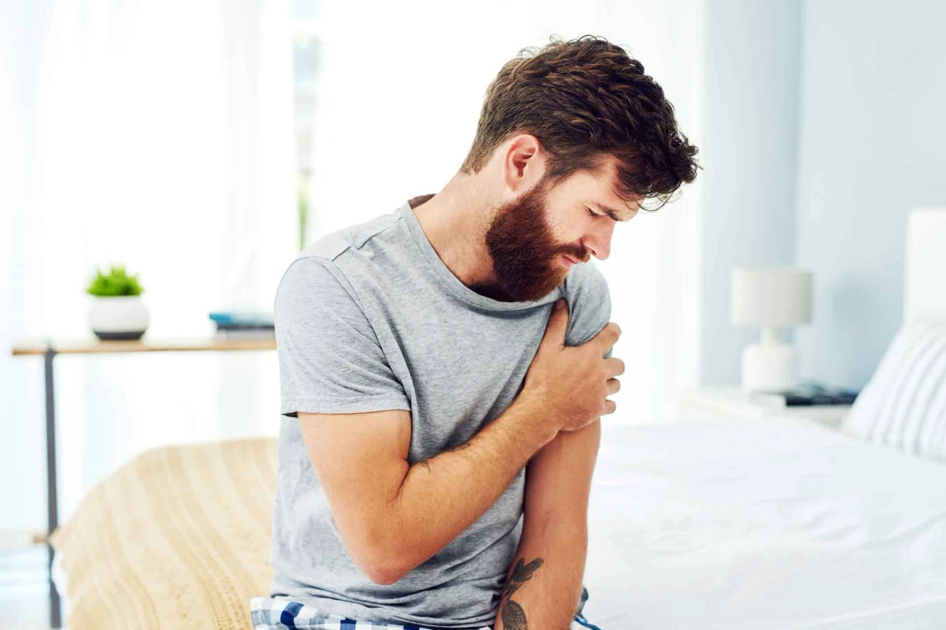 Homme tenant le haut de son bras près de l’épaule.