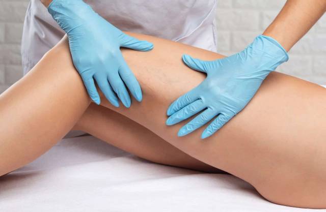 Mains gantées examinant la jambe d’une personne allongée.