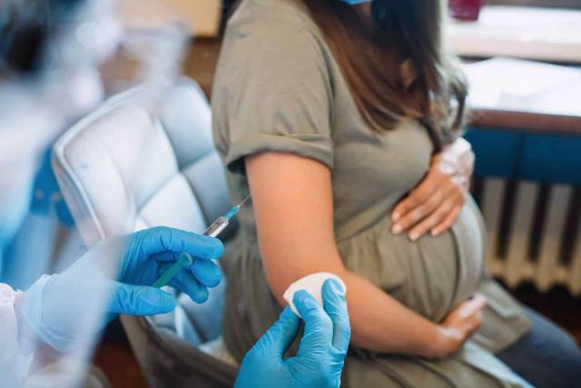 Professionnel préparant une injection dans le bras d’une femme enceinte.