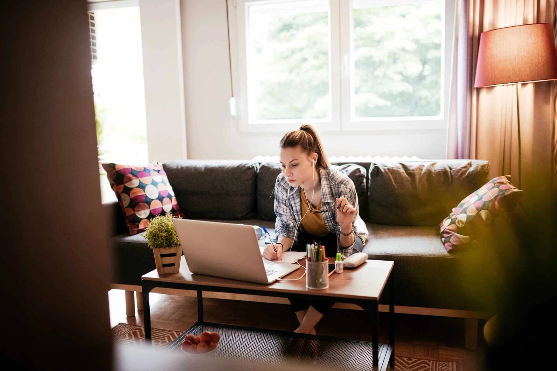 Femme assise chez elle devant un ordinateur portable.