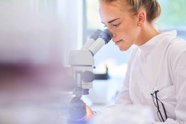 Professionnelle regardant dans un microscope.