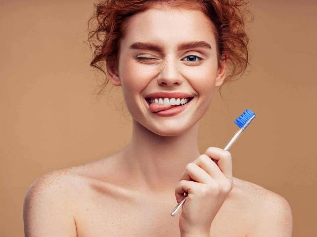 Femme souriante tenant une brosse à dents.