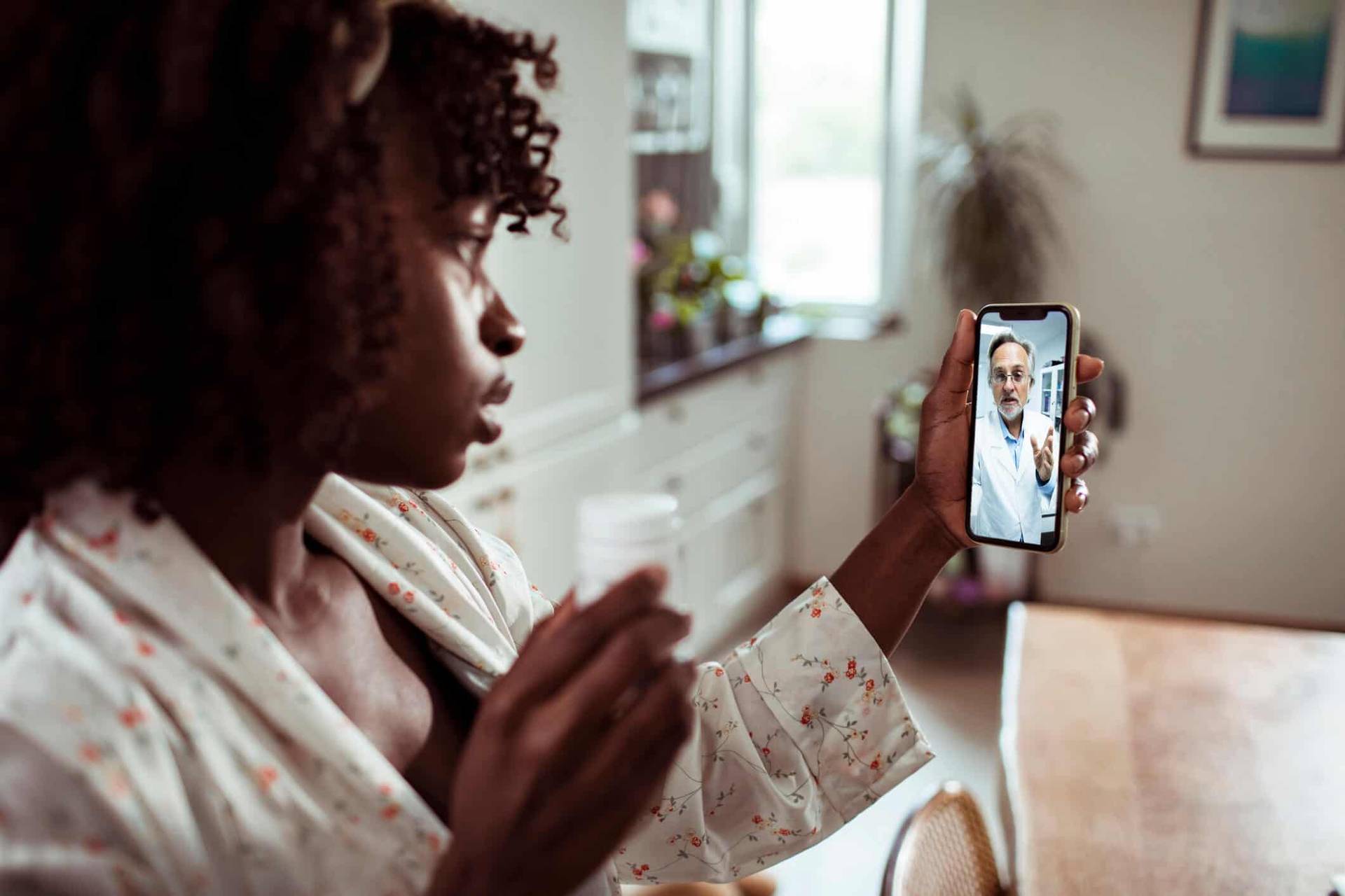 Femme échangeant en vidéo avec un professionnel sur son téléphone.