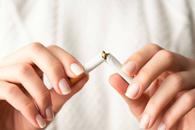 Mains brisant une cigarette.