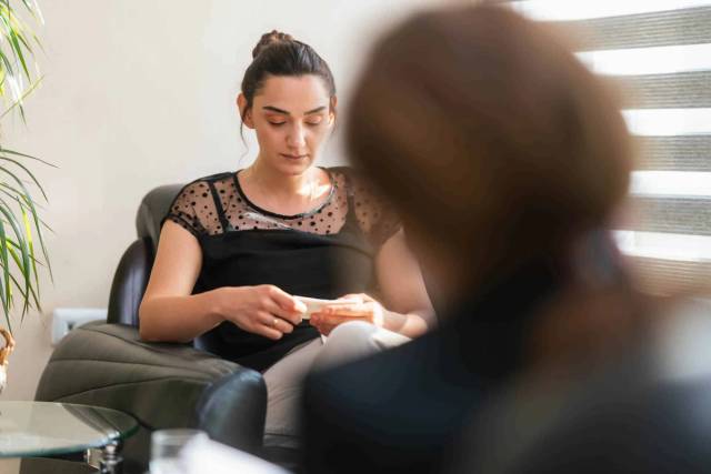 Femme assise en entretien avec une personne tenant un carnet.