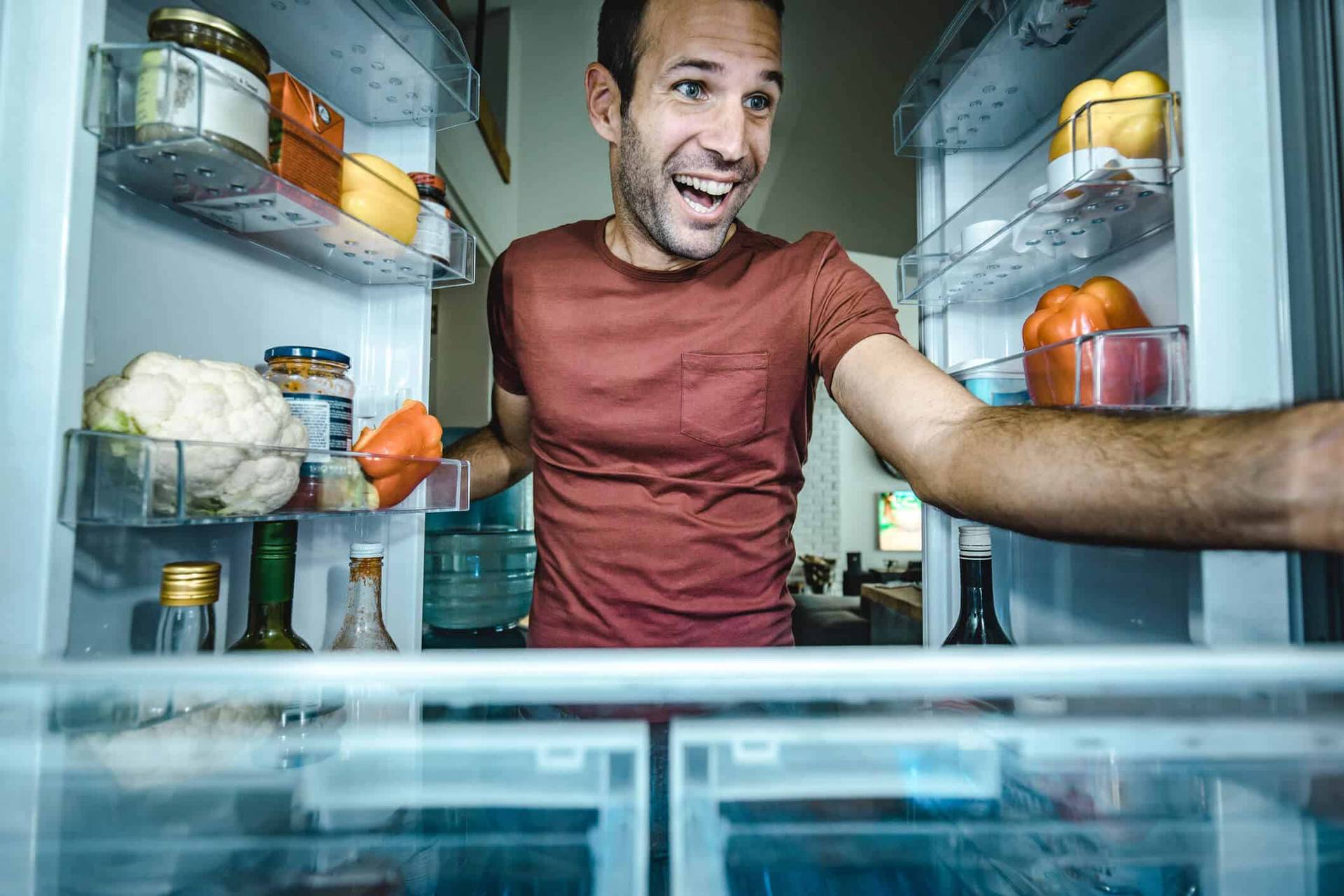 Homme ouvrant un réfrigérateur rempli d’aliments.