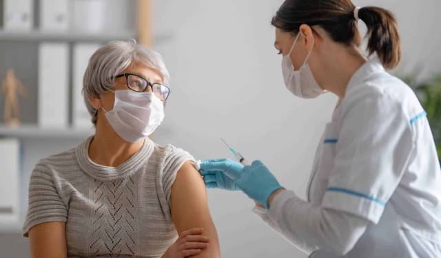Professionnelle en blouse blanche préparant une injection dans le bras d’une femme.