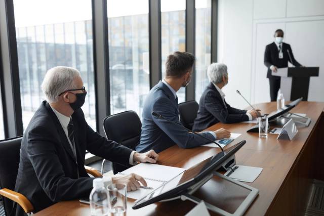 Des professionnels discutant dans une salle de conférence avec des mesures de sécurité comme des masques