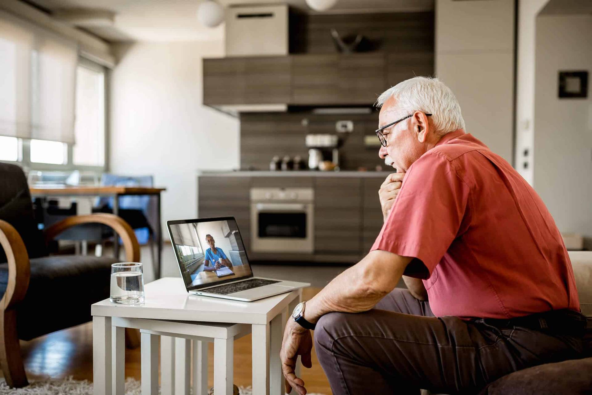 Homme assis face à une consultation vidéo sur ordinateur.