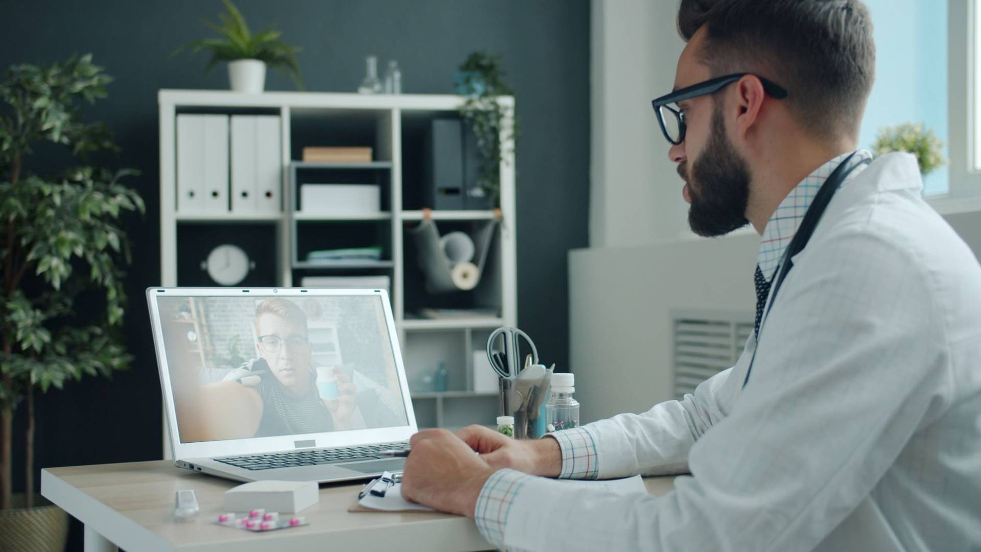 Médecin échangeant en vidéo avec une personne sur son ordinateur portable.