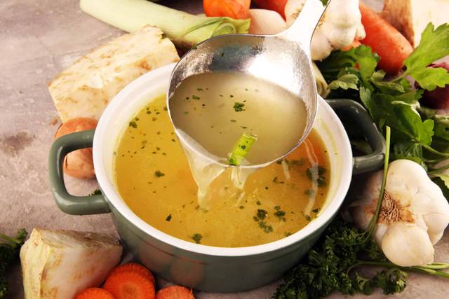 Louche versant un bouillon dans une casserole.