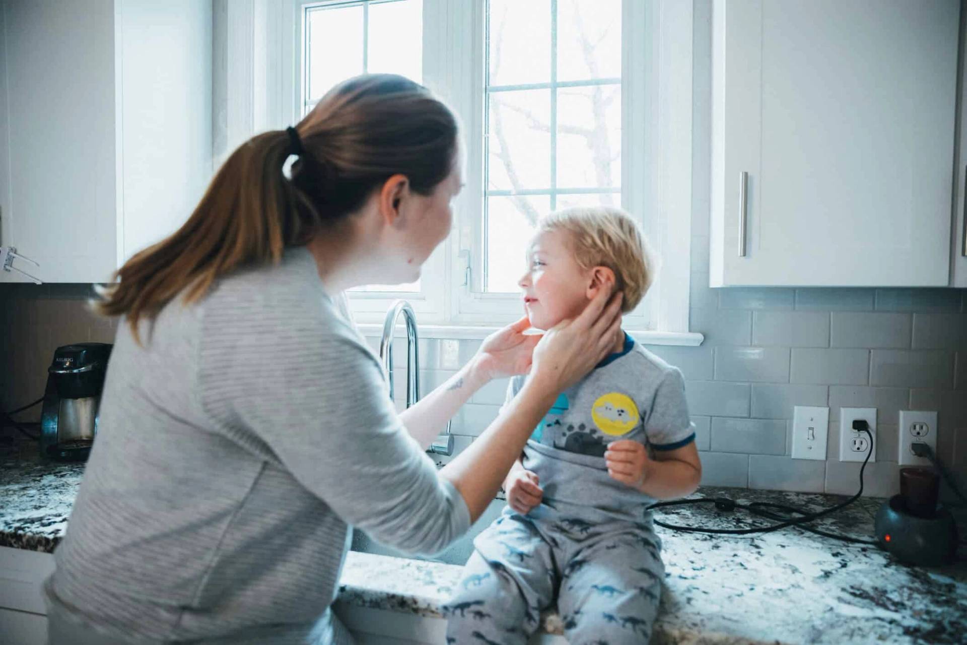 Adulte examinant la joue d’un enfant assis sur un plan de travail.