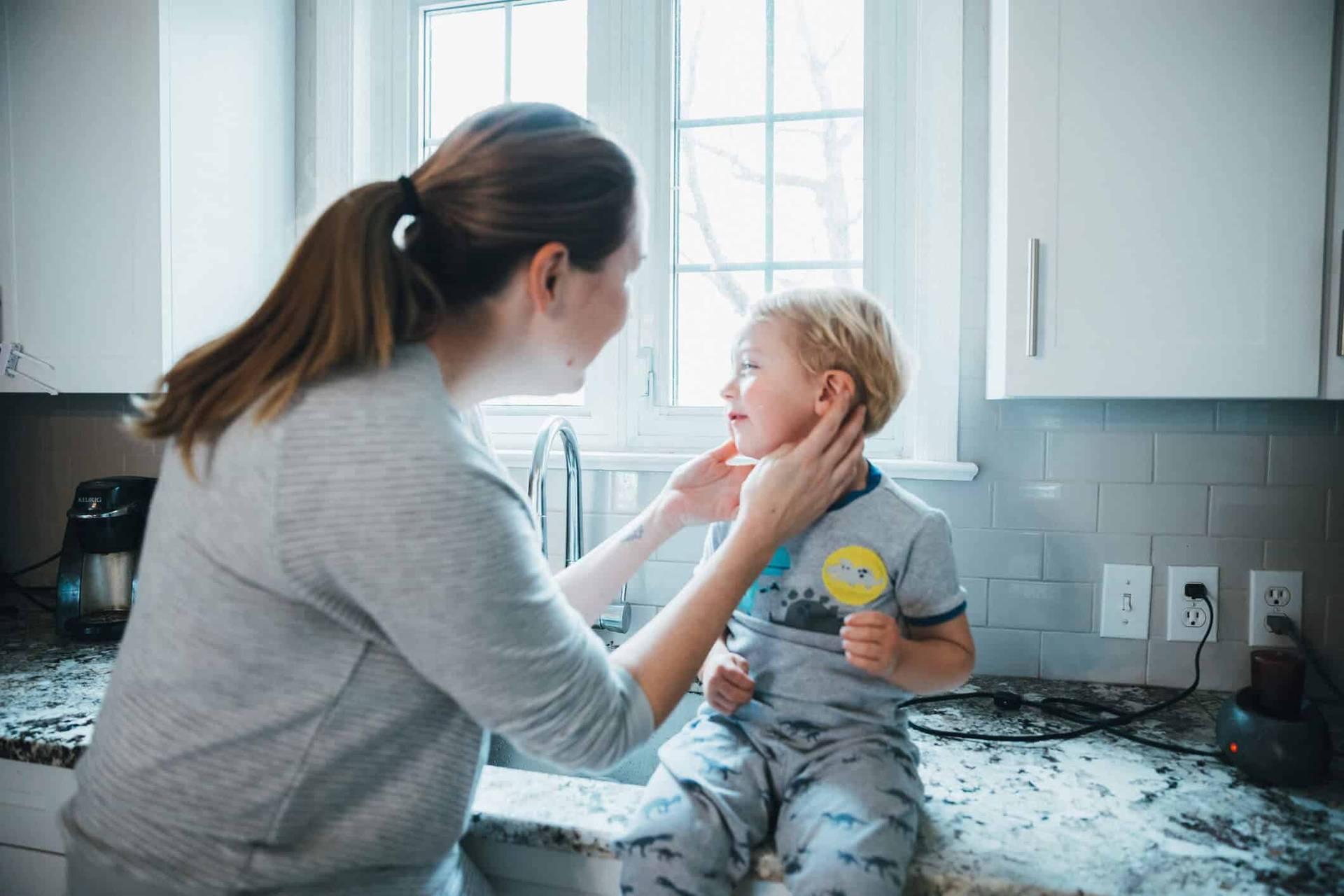 Adulte examinant la joue d’un enfant assis sur un plan de travail.