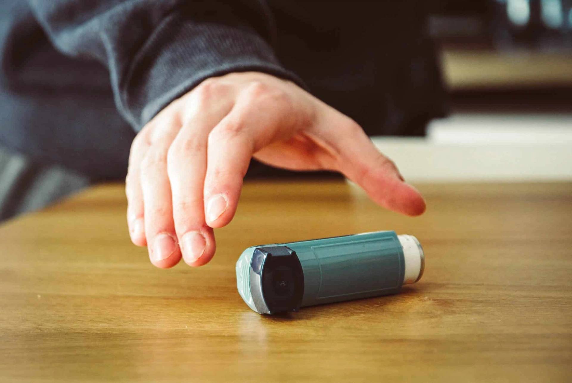 Main se dirigeant vers un inhalateur posé sur une table.