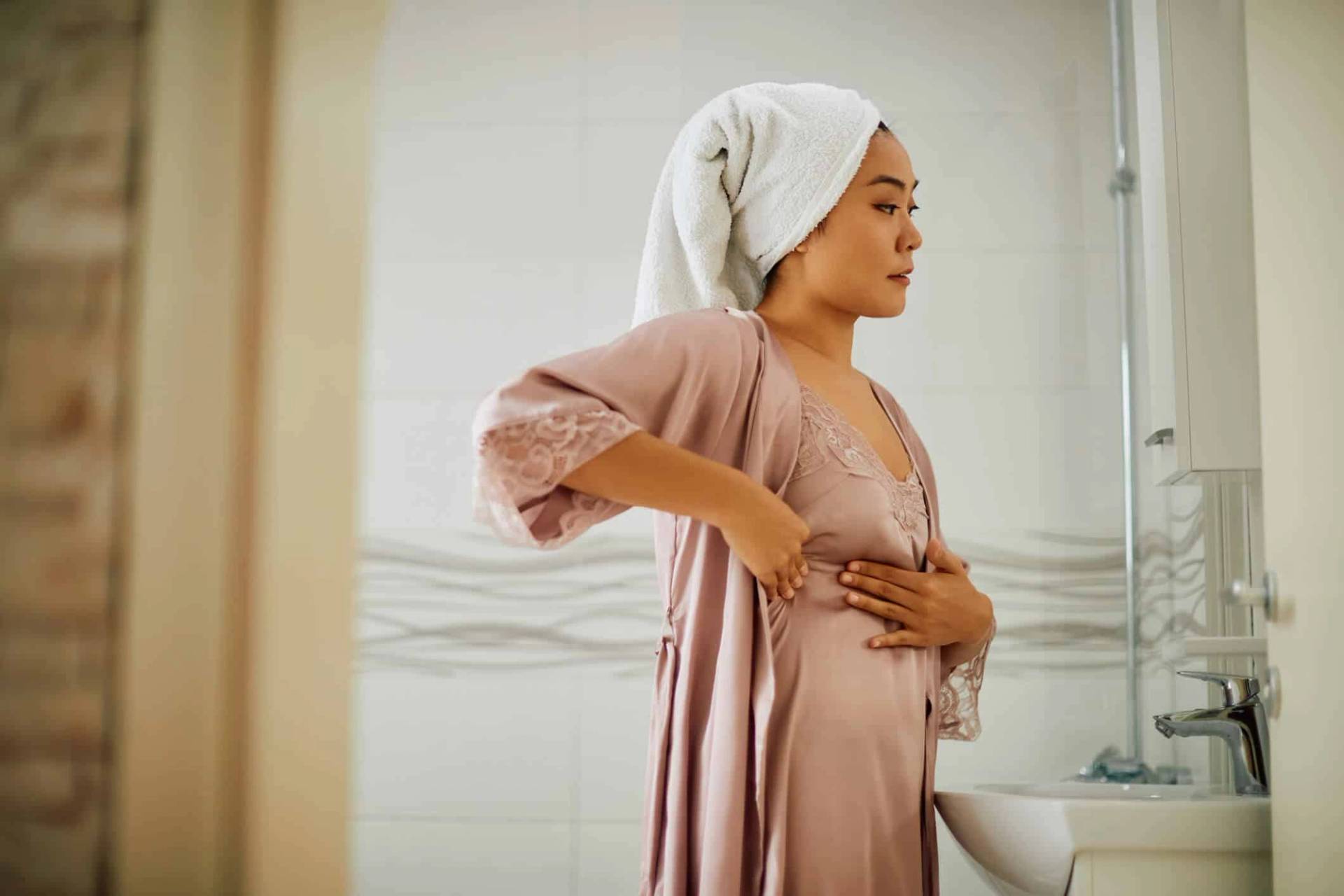 Femme palpant sa poitrine devant un miroir.