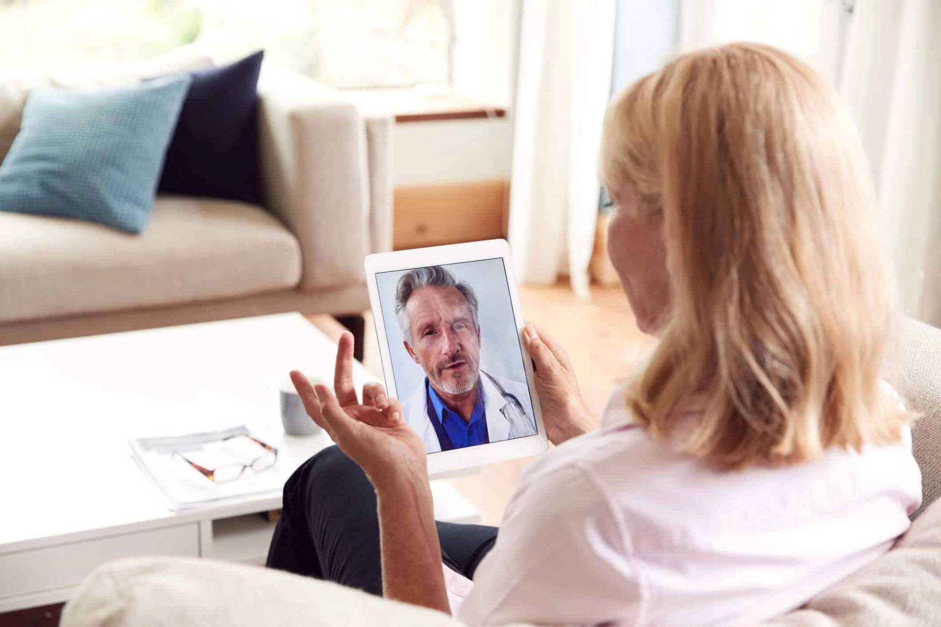 Personne échangeant avec un médecin par appel vidéo sur une tablette.