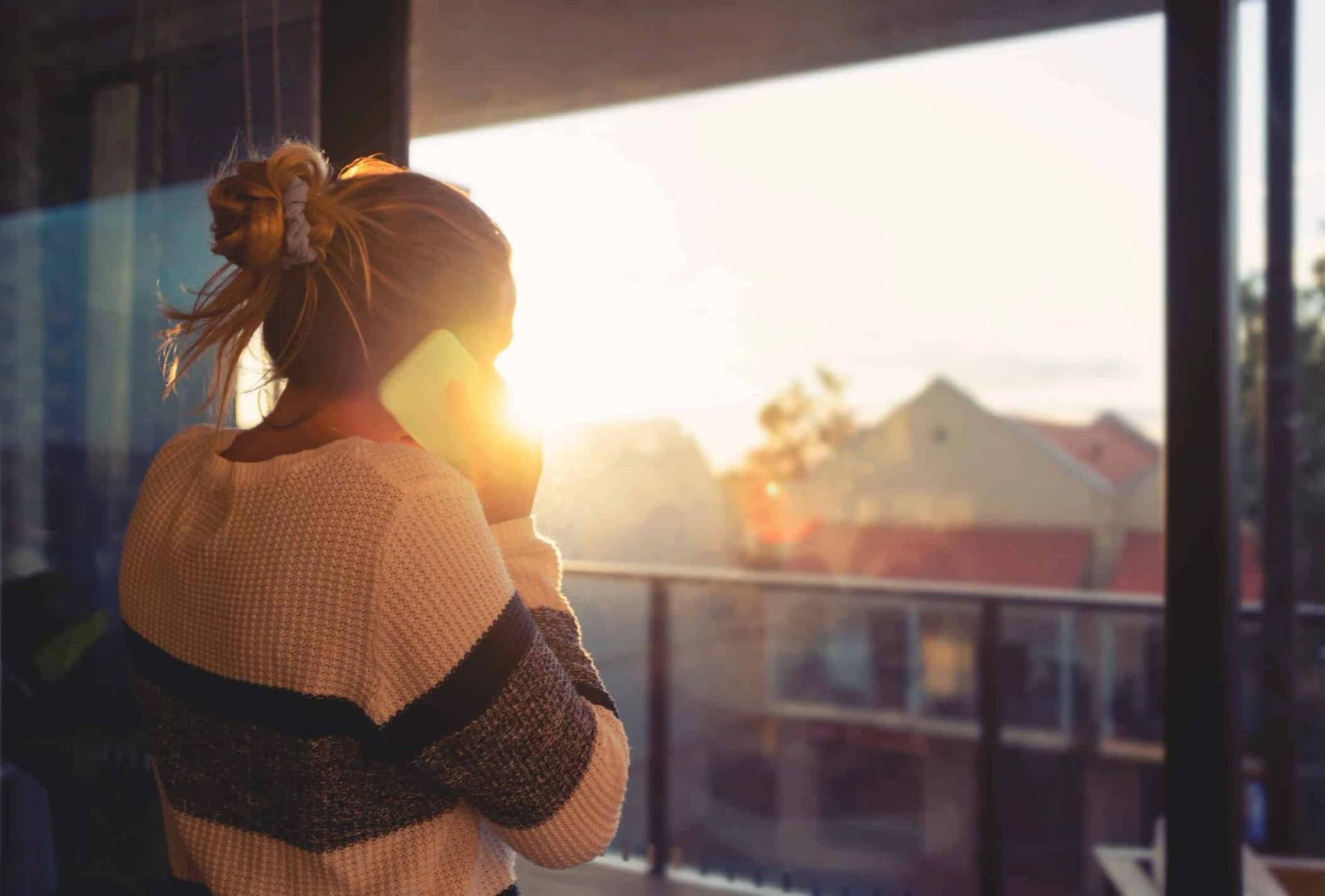 Femme tenant une tasse près d’une fenêtre au soleil.