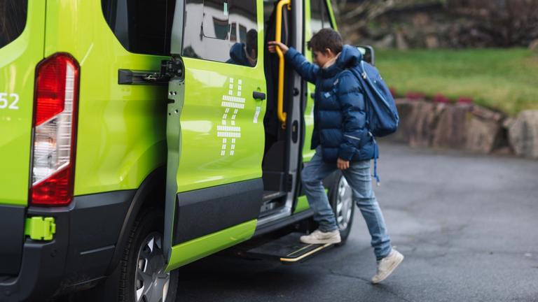 Grønn minibuss henter skolebarn