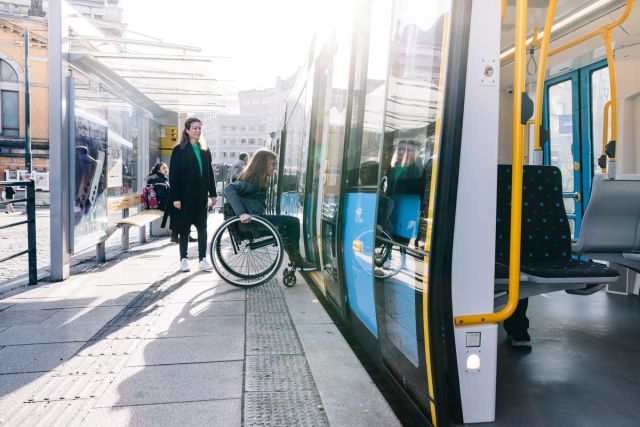 a woman in a wheelchair on her way into a tram