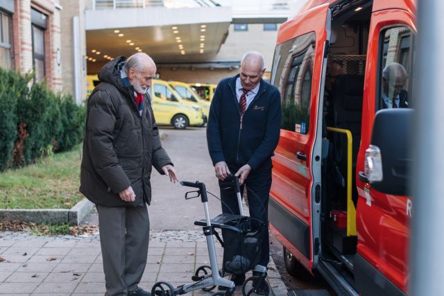 Eldre mann blir hjulpet inn i bilen av sjåfør