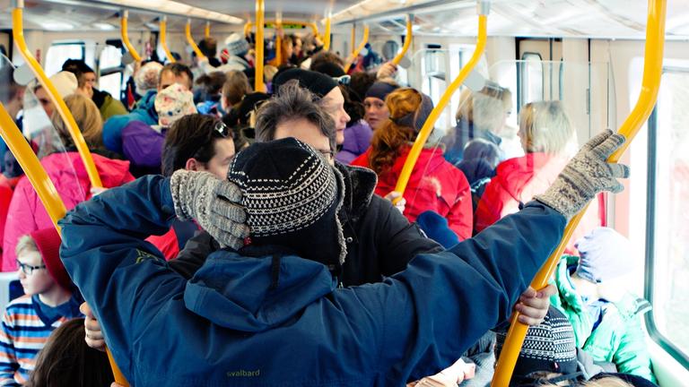 Full t-banevogn hvor folk står tett i tett