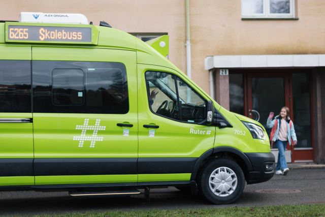 Elev blir hentet av en grønn skoleskyss-bil