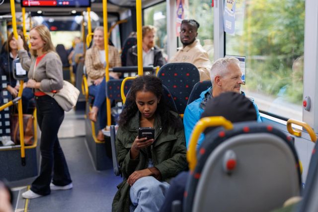 Reisende på buss som sjekker mobil
