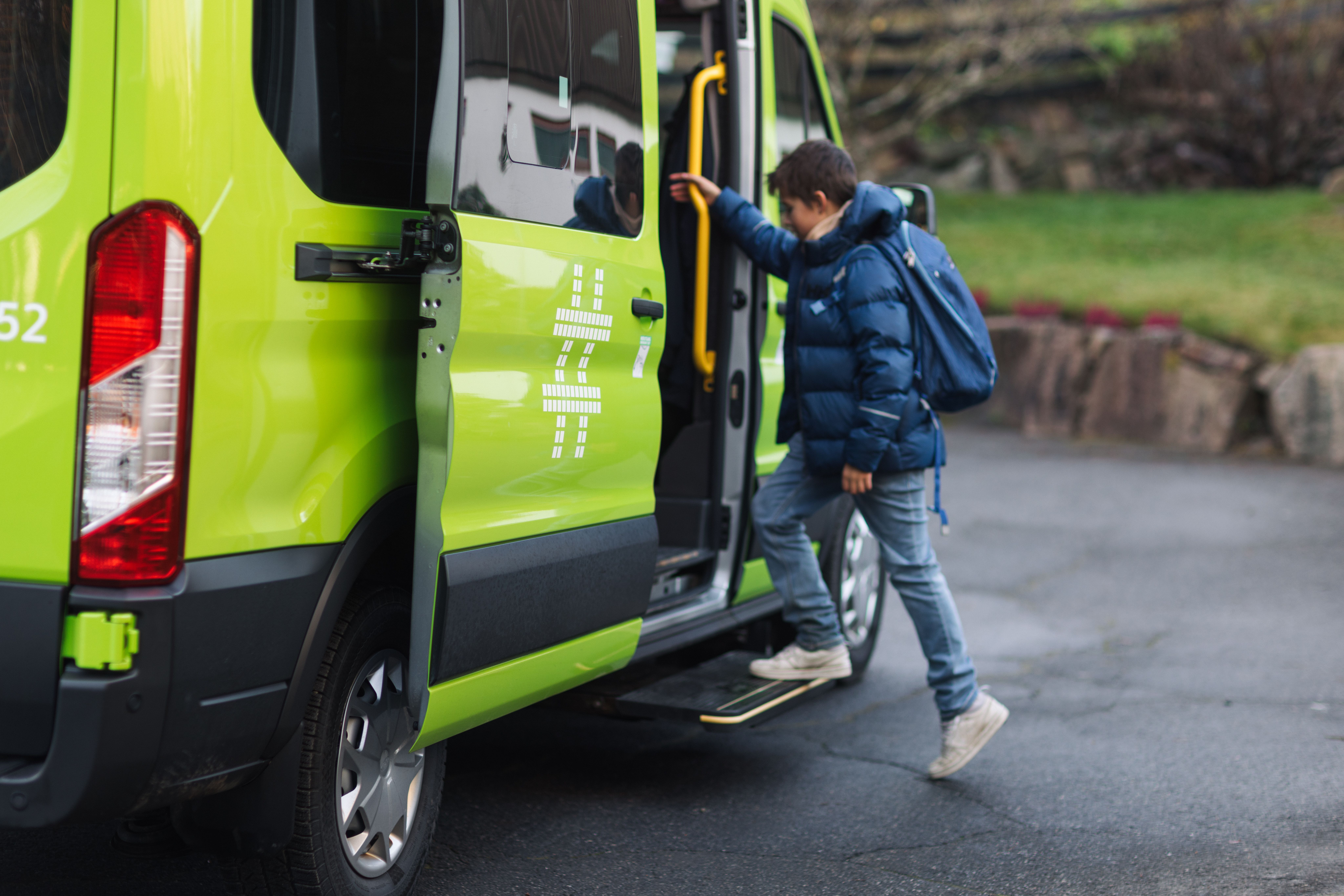 Grønn minibuss henter skolebarn
