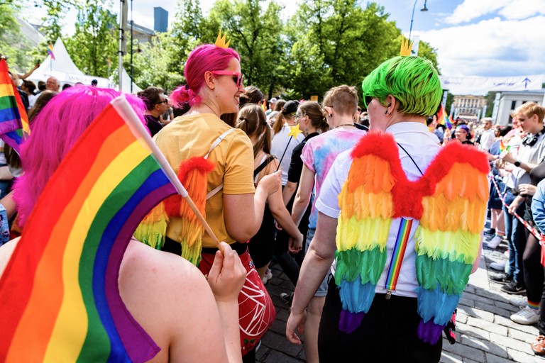People walking in the pride parade with colorful flags and angel wings