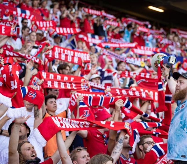 A gang of Norwegian football supporters lifting their scarfs at the arena.
