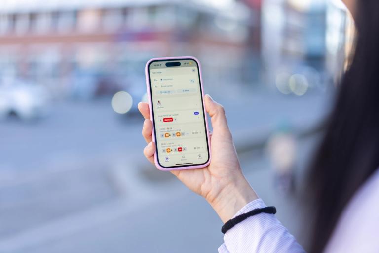 En person holder en mobil og sjekker Hent i Ruter-appen