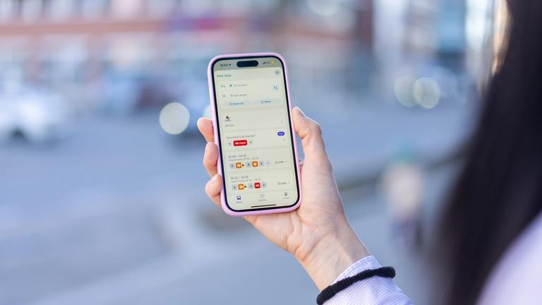 En person holder en mobil og sjekker Hent i Ruter-appen