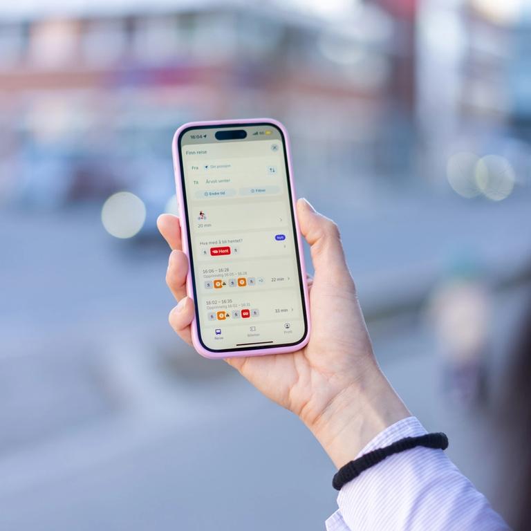 En person holder en mobil og sjekker Hent i Ruter-appen