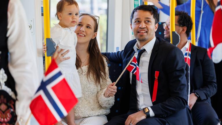 A family is taken the metro on 17th may. Many Norwegian flags