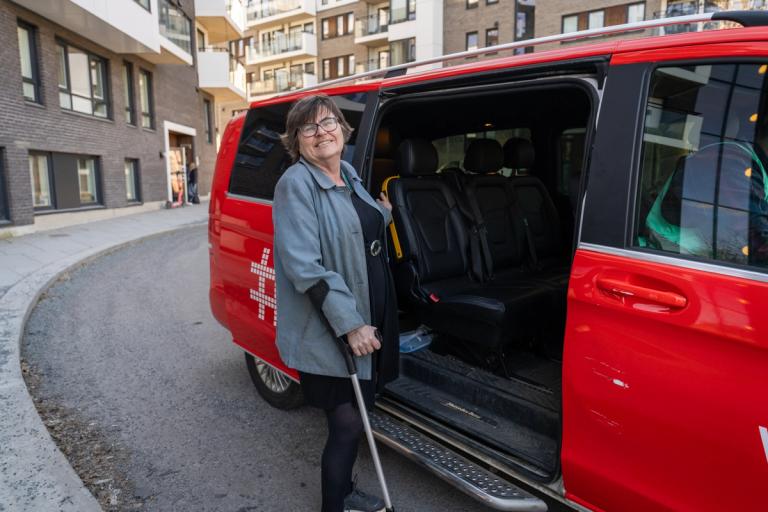 En person med krykke på vei inn i red Hent-bil